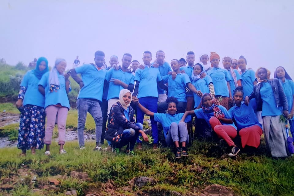 A wide view of the Colas team standing together on the hillside after planting.