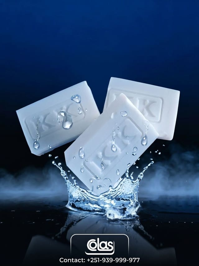 Three white KK bars suspended above a crown of splashing water.